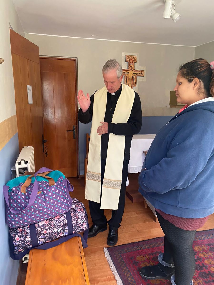 Un sacerdote bendiciendo la casa, acompañado por una de las mamás.