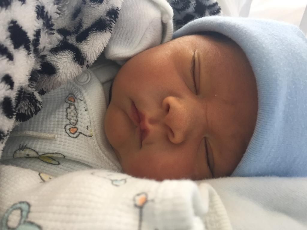 Un recién nacido durmiendo con gorro, arropado en su cuna.