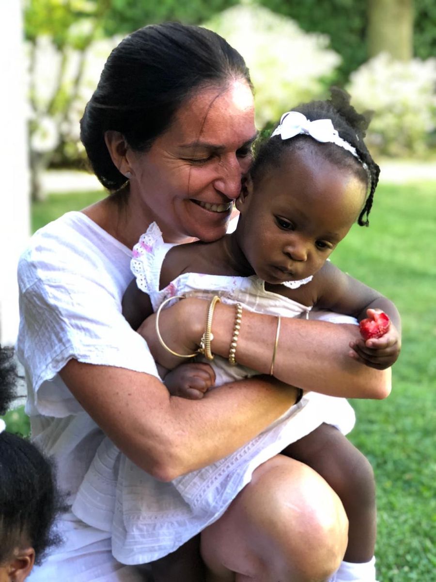 Una voluntaria en el jardín, con una niña pequeña en brazos.